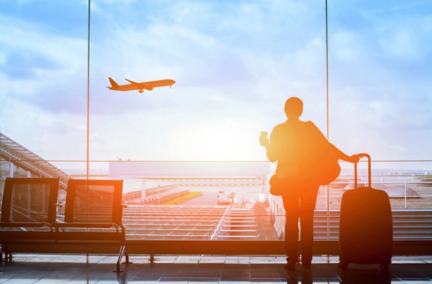 person_at_airport_holding_coffee_and_luggage.jpg